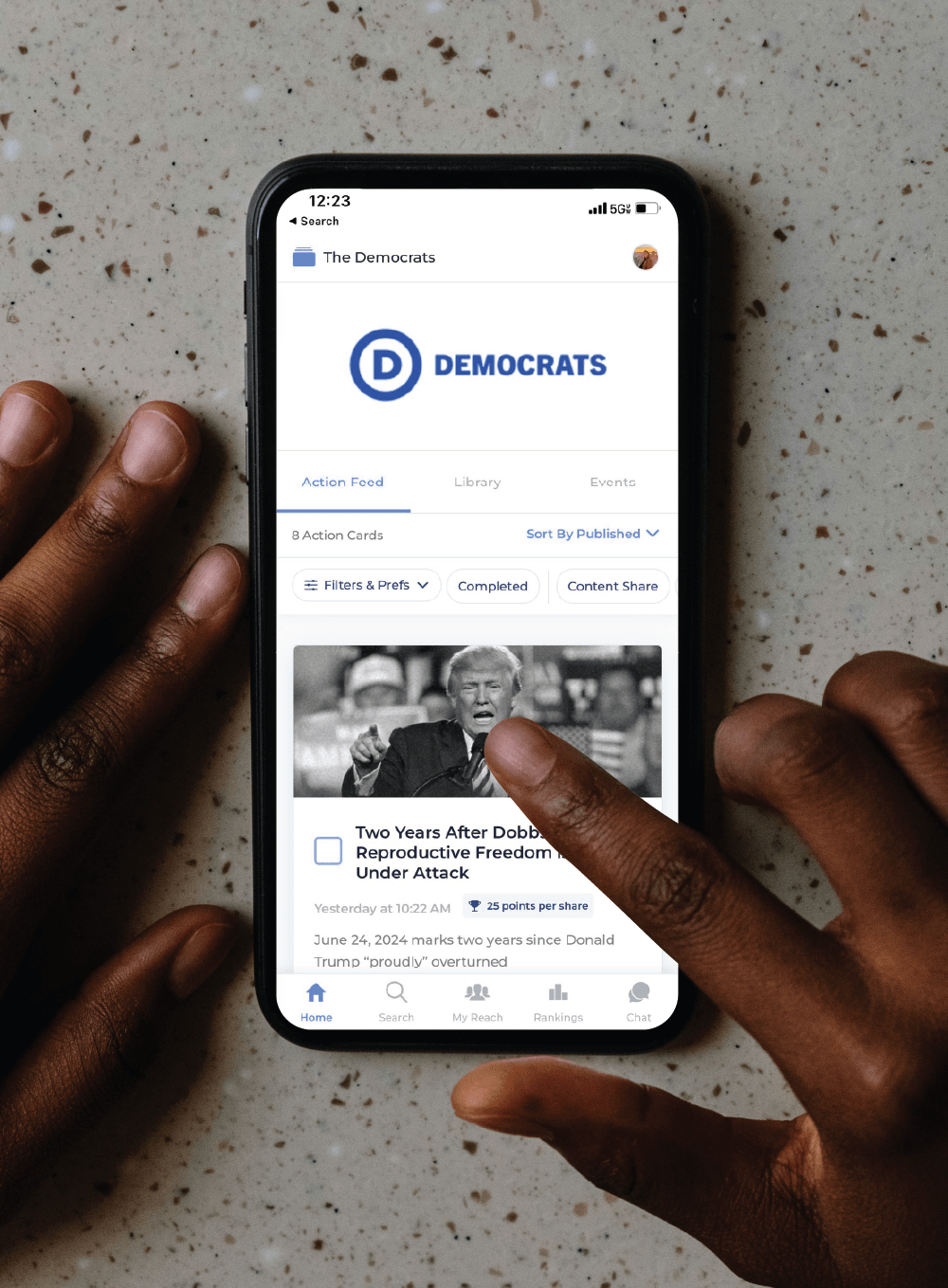 A person looking at a screenshot of the Democratic National Committee's homepage on Reach app on an iPhone