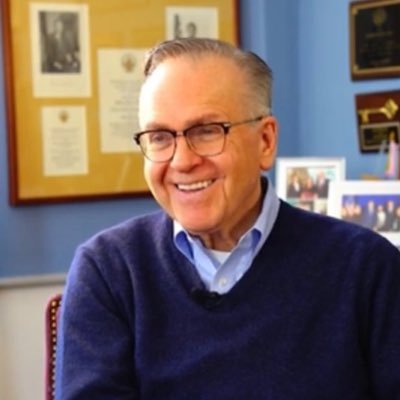 A professional headshot of Ray Buckley, President Emeritus of the ASDC. He is smiling and wearing a dark sweater, glasses against an indoor background.